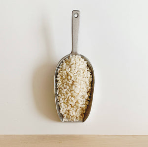 Close up of arborio rice on a metal scoop